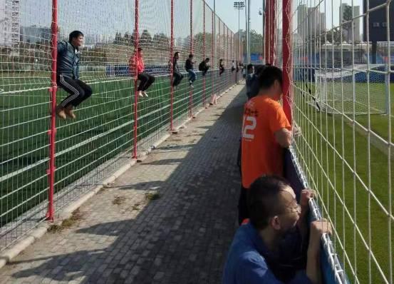 国足选拔队备受追捧，众多武汉球迷爬上铁栅栏观看训练
